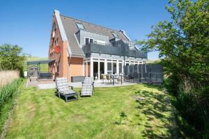 una casa con dos sillas y una mesa en un patio en Haus-Eriel-OG-rechts, en Brösum