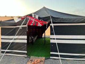 a black and white tent with a pair of shoes in it at Al Badri Bedouin Camp in Al Wāşil