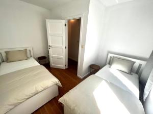 a bedroom with two beds and a door to a hallway at Wolu suites in Brussels