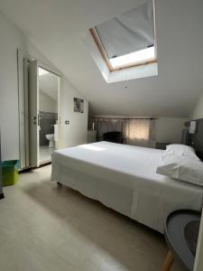 a bedroom with a large white bed and a skylight at Bella Vita Guesthouse -parcheggio privato interno in Arona