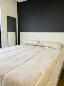 a large bed in a bedroom with a black wall at LOFT UP 1309 | Mobiliado | WIFI | Piscina | in Blumenau +17 photos