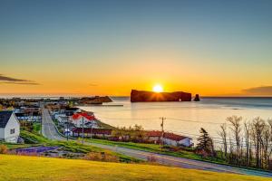 a sunset over a town and a body of water at Riotel Perce in Perce