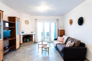 a living room with a couch and a tv at SounioKallisti Suites 3 in Análipsis