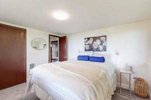 ein weißes Schlafzimmer mit einem großen Bett mit blauen Kissen in der Unterkunft Sea Bell Retreat in Phippsburg