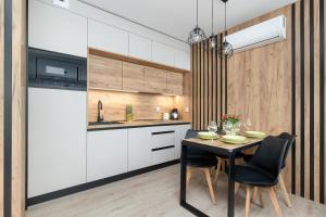 a kitchen with a black table and chairs at Exclusive Apartments Porta Mare Marina - Swimming Pool & Sauna by Renters Prestige in Dziwnów