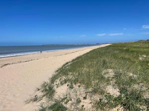 une plage de sable avec de l'herbe et l'océan dans l'établissement L'aventurine NO, à Barbâtre