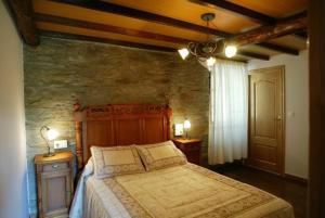 1 dormitorio con 1 cama grande en una pared de piedra en Costa da Egoa en Carral