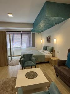 a bedroom with a bed and a couch and a table at Gardenia Hotel & Spa in Veles