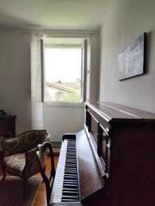 a room with a piano and a chair and a window at La Belle Epoque in Gubbio