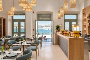 a restaurant with tables and chairs and a view of the ocean at YeeOn Boutique Hotel, Gythio - Historic Hotels of Europe in Gythio