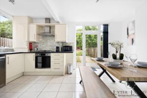 une cuisine avec des armoires blanches et une table en bois dans l'établissement The Oakleigh - Fosse Park - Close to M1 and M69 - 3 Bed House, Contractors, Corporates, MonthlyStays, à Glen Parva