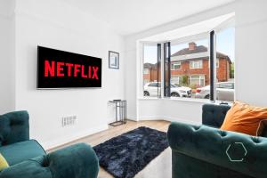 - un salon avec 2 chaises vertes et un panneau netflix sur le mur dans l'établissement The Oakleigh - Fosse Park - Close to M1 and M69 - 3 Bed House, Contractors, Corporates, MonthlyStays, à Glen Parva