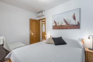 a white bedroom with a bed and a desk at Apartments Bellissima in Funtana