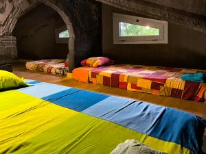 two beds in a room with colorful sheets on the floor at Black House- Sorprendente casa estilo industrial in Olot +38 photos