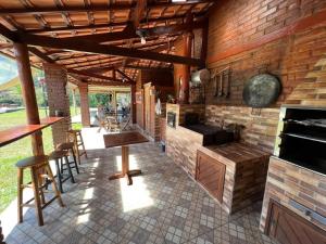 an outdoor kitchen with a brick wall and tables and chairs at Pousada Caminho dos Ventos in Passa Quatro