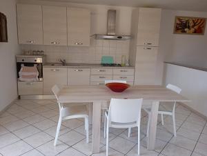 Una cocina con una mesa de madera y sillas blancas. en Casa vacanze da viola, en Ugento