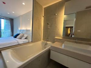 a bathroom with a tub and a sink and a bed at The Astra Residence in Chiang Mai