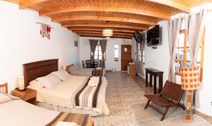 a hotel room with two beds and a chair at Casa Lickana B&B in San Pedro de Atacama