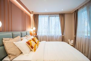 a bedroom with a bed with pillows and a window at Victoriei Emerald & Pink Gems - Designer Apartments in Bucharest