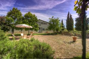 Una casa con una sombrilla y sillas en un patio. en allegretti appartamento aia, en Castelnuovo Berardenga