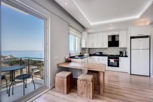 a kitchen with white cabinets and a large window at Begonvilla Homes Karaöz in Karaoz