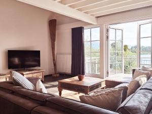 a living room with a couch and a tv at Strandhaus Chiemsee in Übersee