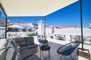 Un patio con un sofá y sillas en un tejado. en Baron Faro - Guest House, en Faro