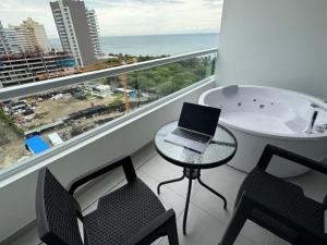 a bathroom with a bath tub and a laptop on a table at Suite con Jacuzzi, vista al mar y piscinas piso 13 in Playa Bello Horizonte