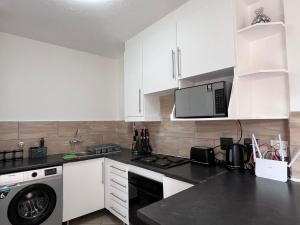 a kitchen with white cabinets and a black counter top at Siena Sun 09 in Midrand