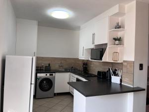 a kitchen with white cabinets and a black counter top at Siena Sun 09 in Midrand