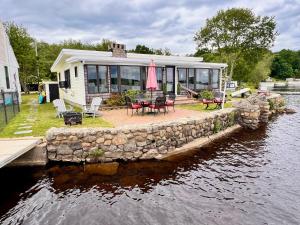 a house with a stone wall next to a body of water at Shoreline Dreams in Lakeville