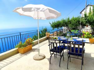 a table and chairs with an umbrella on a balcony at Villa Alba d'Amalfi - The dawn one step from the Heaven in Amalfi