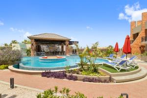 una piscina con sillas y sombrillas en un resort en Bocobay Porta al Sole - Luxury Condos 5 min Walk to Ritz and Palm Beach, en Palm-Eagle Beach
