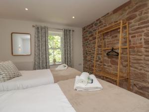 a bedroom with two beds and a brick wall at Heather's Cottage in Carlisle
