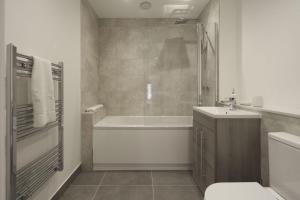 a bathroom with a tub and a toilet and a sink at Fantastic 2 Bedroom Apartment in Central Ashford in Ashford