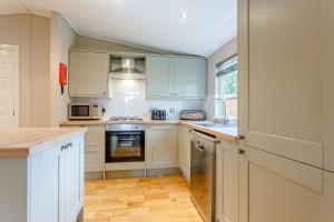 a kitchen with white cabinets and a stove top oven at Blenheim Lodge 21 in Kingham