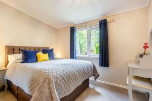 a bedroom with a bed with blue and yellow pillows at Blenheim Lodge 21 in Kingham
