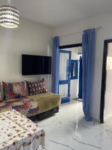 a bedroom with a bed and a couch and a tv at Appartement en location saisonnière in Tetouan