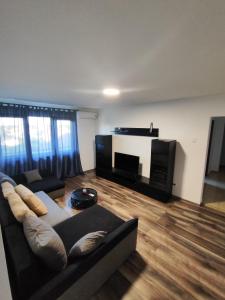 a living room with a black couch and a television at Apartament Luna in Jurilovca