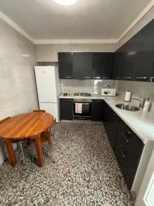 a kitchen with a wooden table and a white refrigerator at Carlota y Vaquero House 2 in Vinaròs +4 photos