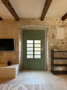 een groene deur in een kamer met een stenen muur bij NEW 2024! Casa Vecchia in Višnjan