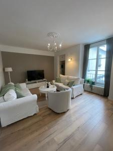 a living room with white furniture and a tv at Appartement hyper-centre vue cathédrale in Beauvais