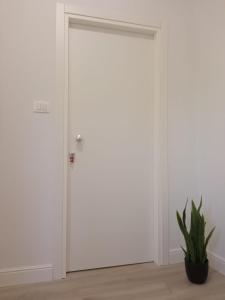 une porte blanche dans une pièce avec une plante dans l'établissement La Casa di Ary alle pendici dell'Etna, à Nicolosi