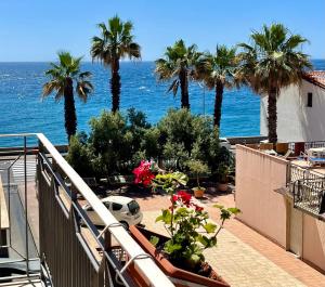 a balcony with palm trees and a view of the ocean at La Casa del Professore in Santa Teresa di Riva