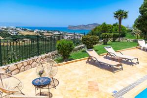 a patio with chairs and a pool and the ocean at Pasiphae villas 1 & 2 in Stalos