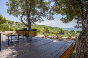 a wooden deck with chairs and a table and a tree at Mobile home Adria in Murter