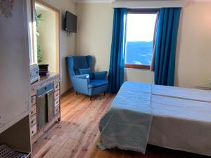 a bedroom with a bed and a blue chair and a window at Riba Loivos Village - Casa C - T3 in Casal de Loivos +30 photos