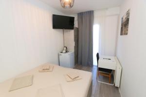 a white room with a white table and a desk at Pansion Comfort Sidro in Novalja