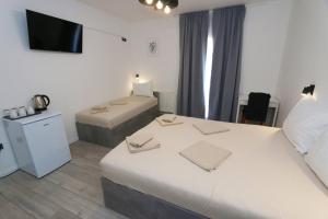 a hotel room with two beds and a flat screen tv at Pansion Comfort Sidro in Novalja