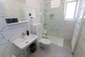a white bathroom with a toilet and a sink at Pansion Comfort Sidro in Novalja